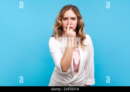 You are liar. Portrait of upset woman with wavy hair in white jacket touching nose showing lie gesture and frowning face, having suspicious about fals Stock Photo