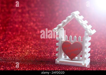 Soft blurred of little white house and red heart against flare light on the red bokeh background for your design pattern or your valentine concept Stock Photo