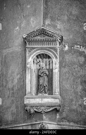 A grungy edit of a small statue niche of the Virgin Mary holding Baby Jesus on the corner of a building in Rome, Italy Stock Photo
