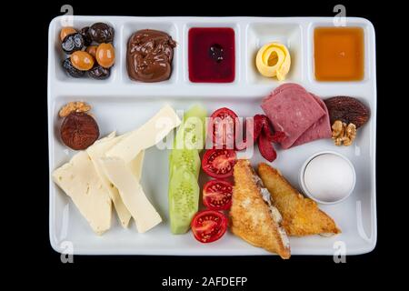 Traditional Turkish breakfast platter on the black wooden table, top view: pogaca pasties, vegetables, cheeses, olives and halal salami, selective foc Stock Photo