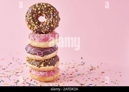 Stack of colorful donuts decorated on pink background Stock Photo