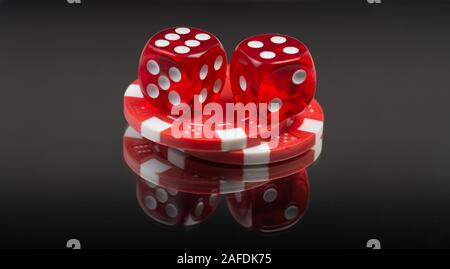 Red dices and casino chips on gradient black mirror background Stock Photo