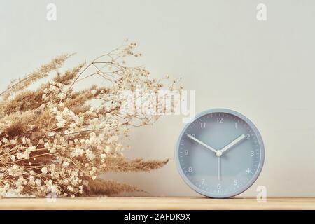 Alarm clock and homemade vase with dries plant on wooden table Stock Photo