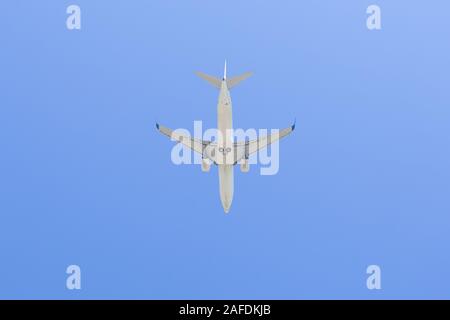 Commercial airline flying on blue sky under view. Stock Photo