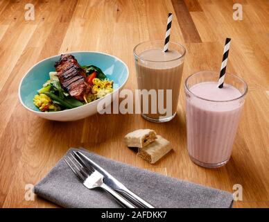 Calorie controlled daily meal plan, including breakfast milkshake, a snack and evening meal of delicious chicken, shot on a wooden background Stock Photo