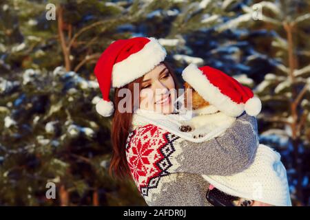 Jack Russell Terrier dog in red Santa hat with owner woman in the winter outdoors. Stock Photo