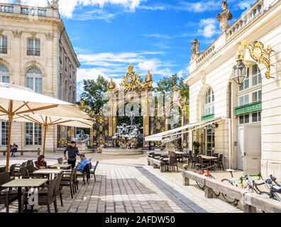 People at a sidewalk cafe on the Stanislas square in Nancy, France, with the fountain of Neptune and its gilded wrought iron portico in the background Stock Photo