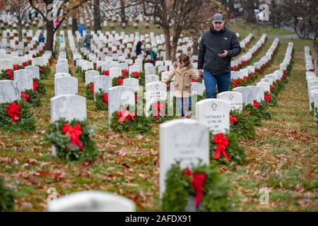Arlington, United States of America. 14 December, 2019. Family members walk past gravesites of fallen service members marked by wreaths during the 28th Wreaths Across America Day at Arlington National Cemetery December 14, 2019 in Arlington, Virginia. More than 38,000 volunteers place wreaths at every gravesite at Arlington National Cemetery and other sites around the nation.  Credit: Elizabeth Fraser/DOD/Alamy Live News Stock Photo