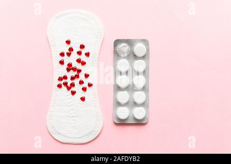 Two pills and menstruation pad with red hearst on it, painkiller contraception medication concept Stock Photo