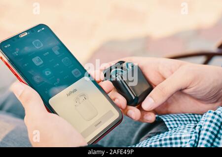 Bishkek, Kyrgyzstan - October 10, 2019: Man holds custom black airpods and connects them to iphone 11 Stock Photo