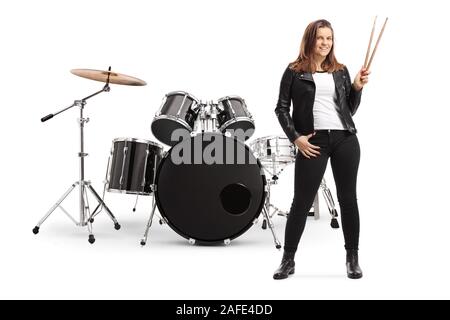 Full length portrait of a young female posing with a drum set and holding drumsticks isolated on white background Stock Photo