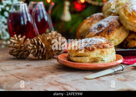 Homemade Christmas puff pastry mince pies with Christmas tree in the background Stock Photo