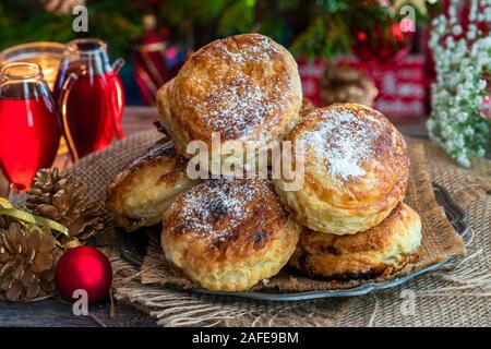 Homemade Christmas puff pastry mince pies with Christmas tree in the background Stock Photo