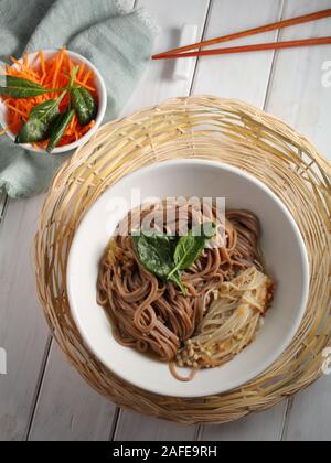 Japanese soup with Enoki mushrooms, soba noodles, spinach, carrot, and soy sauce Stock Photo