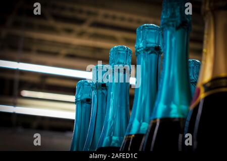 Necks of champagne bottles in foil on  shelf. Vignette. View from below. Stock Photo