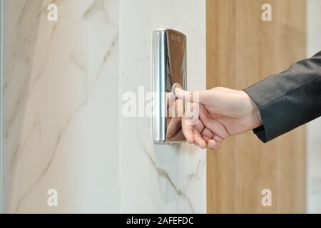 Hand of businessman pushing button on the wall while standing by elevator door Stock Photo