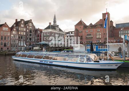 Amsterdam, Netherlands - February 24, 2017: Sightseeing boat with tourists is at the canal in historical center of Amsterdam Stock Photo