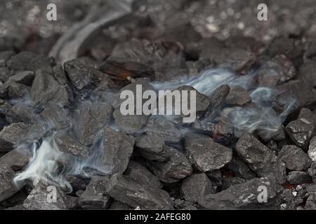 Smoke over the coals of a blacksmith's brazier where the iron horseshoe is annealed Stock Photo