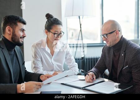 Mature agent consulting his business partners looking through financial contract Stock Photo