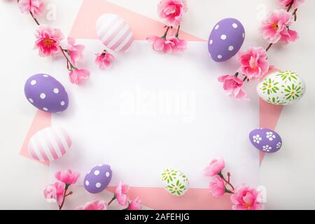 Easter frame of different size Easter eggs and colorful paper over a white background. Easter eggs top view, flat lay. Stock Photo