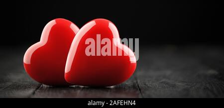 Two red hearts on a wooden table on a dark background. Valentines day card Stock Photo