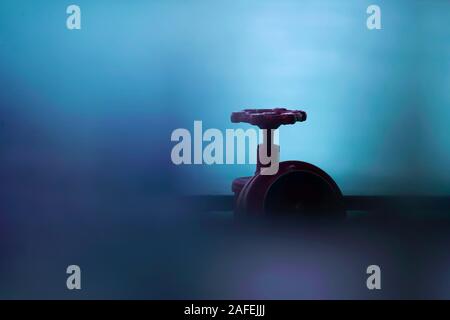 Selective focus on a mains metallic valve with blue background Stock Photo