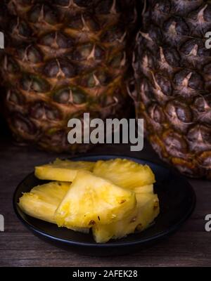 Sliced pineapple on old rustic desk Black background. Stock Photo