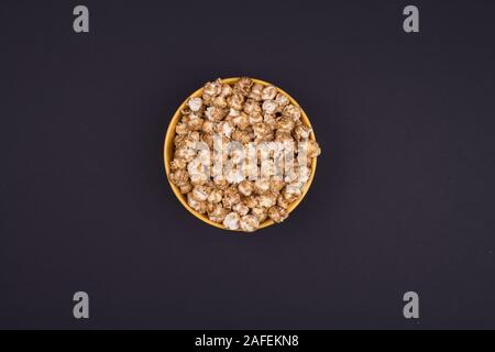Caramel sweet popcorn bowl isolated on black background top view. Frame composition with copy space. Stock Photo