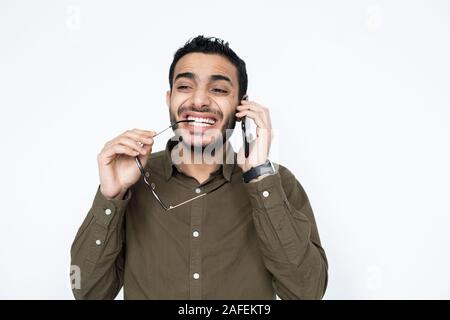 Mixed-race businessman with smartphone by ear and eyeglasses talking to client Stock Photo