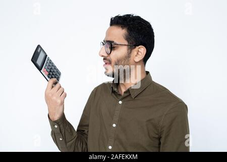 Young male accountant or student in eyeglasses looking at calculator in his hand Stock Photo