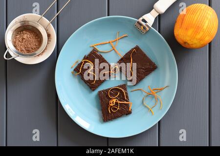 Yummy handmade chocolate candy bars with orange peels on turquoise plate overhead view Stock Photo
