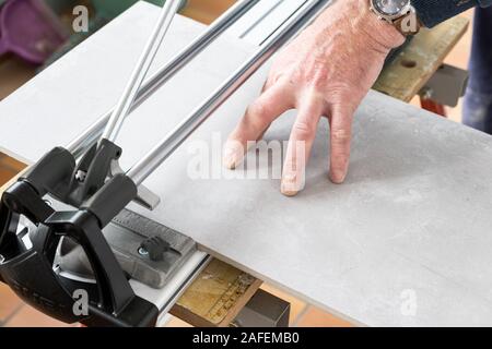 the mason cuts a ceramic tile with a tile cutter Stock Photo