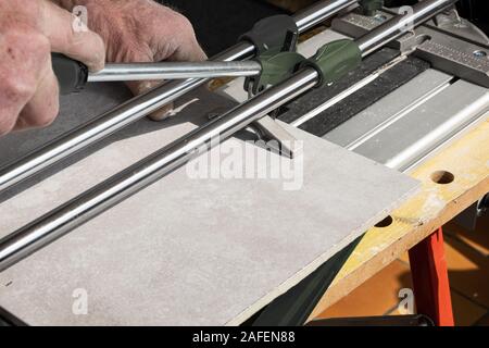 the mason cuts a ceramic tile with a tile cutter Stock Photo