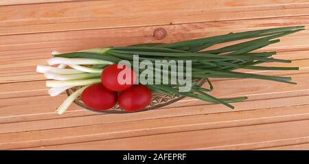 Spring onions and Easter red eggs on wooden background Stock Photo