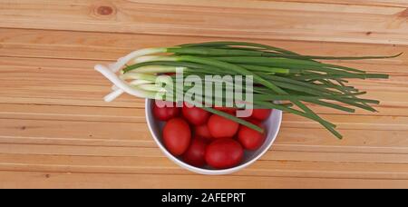 Spring onions and Easter red eggs on wooden background Stock Photo