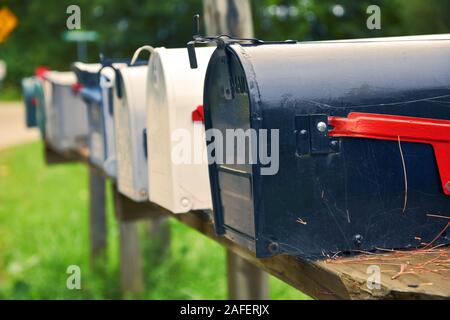 An isolated row of metal US mail boxes on wooden post in the countryside. Spider webs in one of them. Mail concept. New York City. United States. Stock Photo