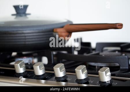 Close-up of a pan with a wooden handle on a gas stove, selective focus Stock Photo