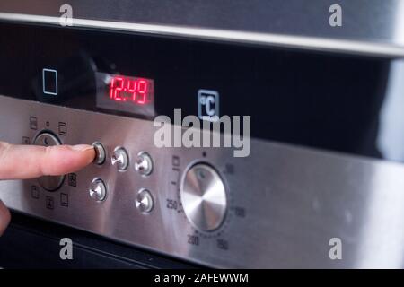 Close-up male hand selects the operating mode of the oven, selective focus Stock Photo