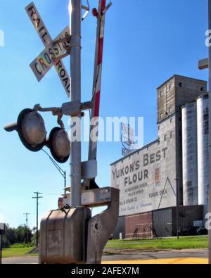 Main Street Yukon Oklahoma sports Yukon's Best Flour grain elevator and a railroad crossing signal and arm. Stock Photo