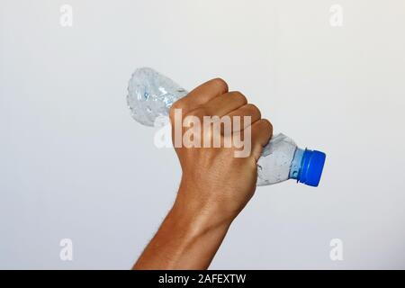 Hand squeezing Plastic Bottle representing movement against pollution and for recycling. Stock Photo