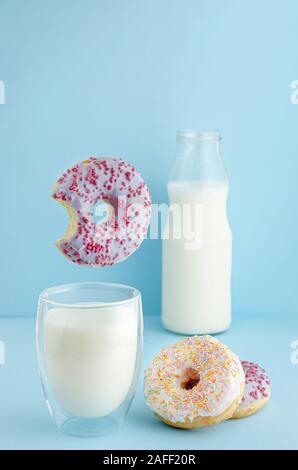Flying food concept. Delicious breakfast with glass of milk and doughnuts on pastel blue background with copy space. Stock Photo