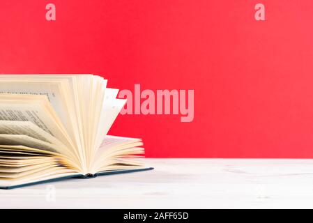 Composition with vintage old hardback book, diary, fanned pages on wooden deck table and red background. Stacking books. Back to school. Copy space Stock Photo