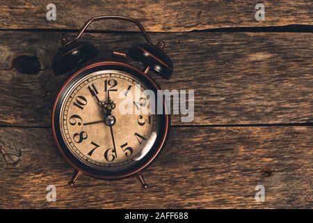 Old retro alarm clock on wooden table. Time is ticking and the hands. Stock Photo