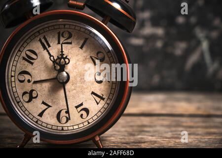 Old retro alarm clock on wooden table. Time is ticking and the hands. Stock Photo