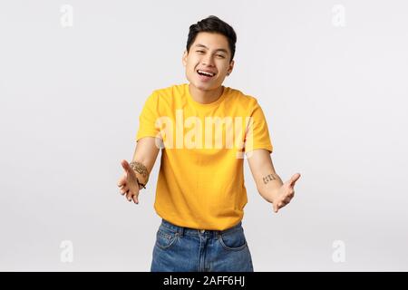 Tender and cute charming asian young boyfriend with yellow t-shirt, return home want hug his lovely dog, stretch hands forward to cuddle, embrace Stock Photo