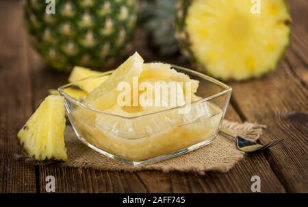 Preserved Pineapple Rings on an old wooden table as detailed close-up shot; selective focus Stock Photo