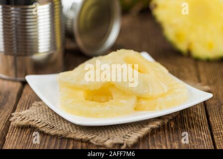 Preserved Pineapple Rings on an old wooden table as detailed close-up shot; selective focus Stock Photo