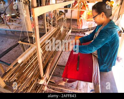 A  female weaver producing silk fabric on a traditional hand loom on Silk Island / Koh Dach near Phnom Penh, Cambodia. Stock Photo