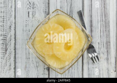 Preserved Pineapple Rings as high detailed close-up shot on a vintage wooden table; selective focus Stock Photo