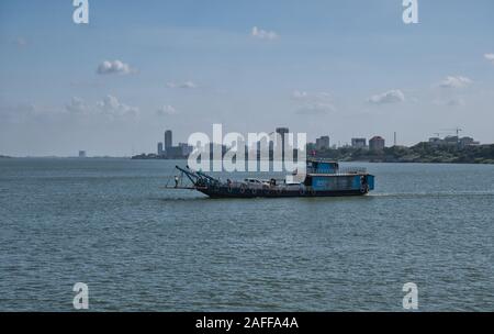 A car ferry crosses the Mekong River between Koh Dach / Silk Island and Phnom Penh, which appears in the background. Stock Photo